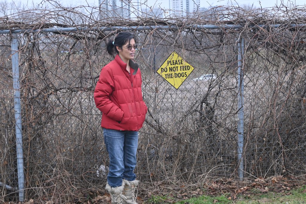 Woman in red winter coat standing in front of "Do Not Feed Dogs" sign